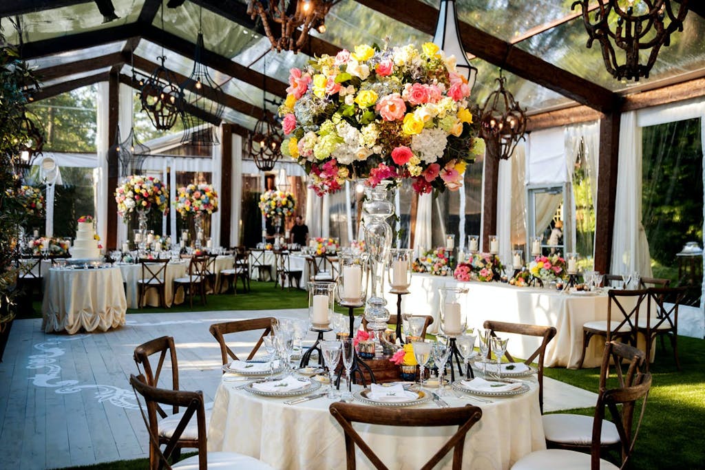 Clear Wedding Tent With Rustic Wooden Beams and Colorful Floral Centerpieces | PartySlate