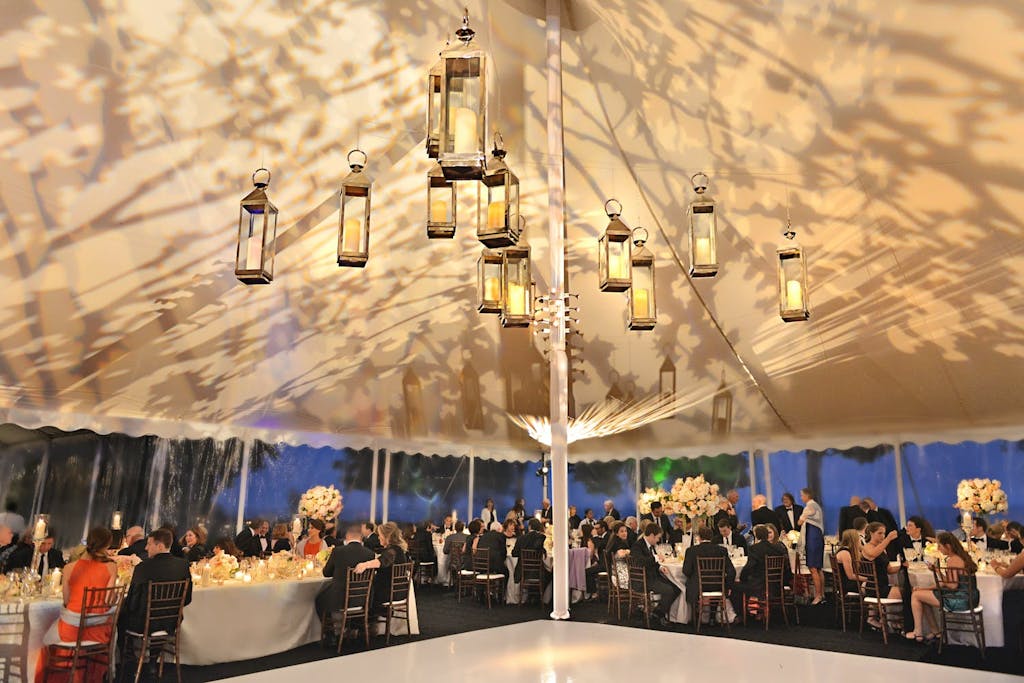 White Pole Wedding Tent with Lantern Ceiling Installation and Shadowy Leaf-Patterned Roof | PartySlate
