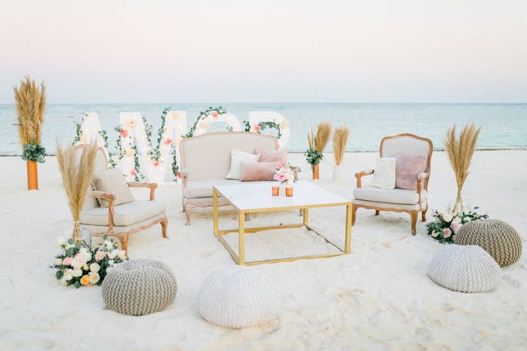 Amor floral sign on the beach with furniture seating | PartySlate