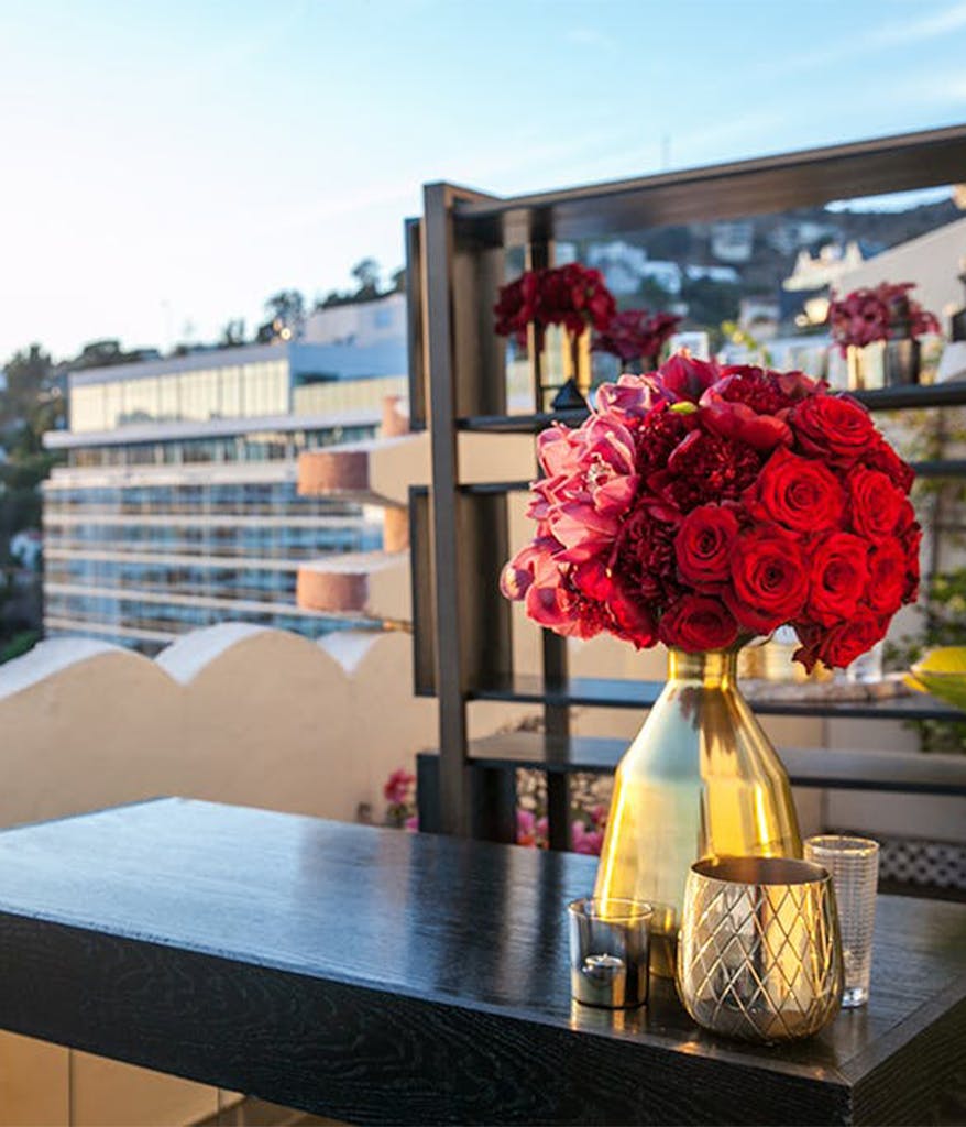 a rooftop birthday party in LA with a black bar, red roses, and gold vases