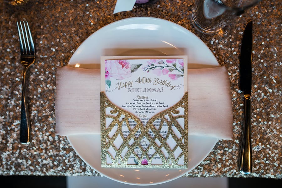 40th-Birthday Party Table Setting With Light Pink Napkin and Glittering Gold Menu | PartySlate