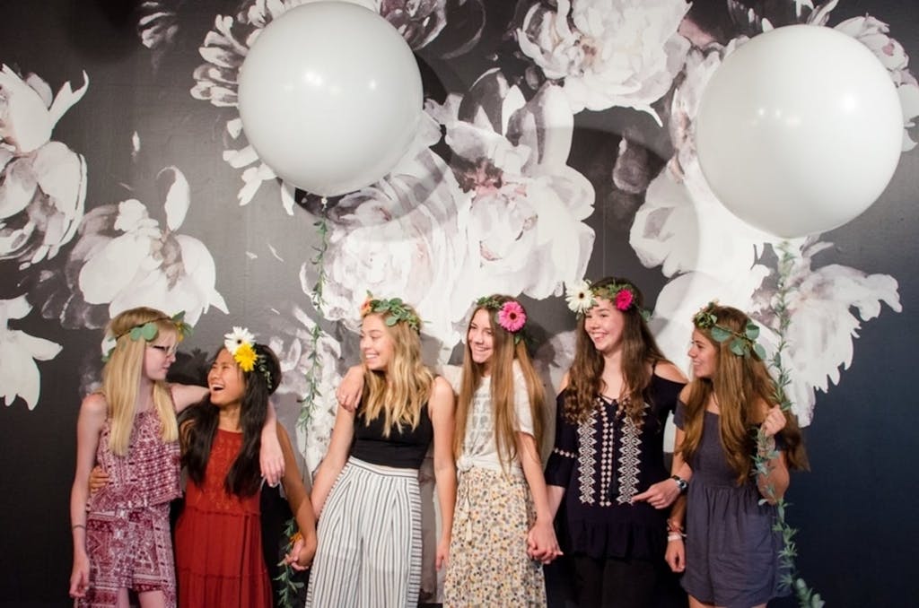 Six Girls Pose in Front of Black and White Floral Backdrop With White Balloons | PartySlate