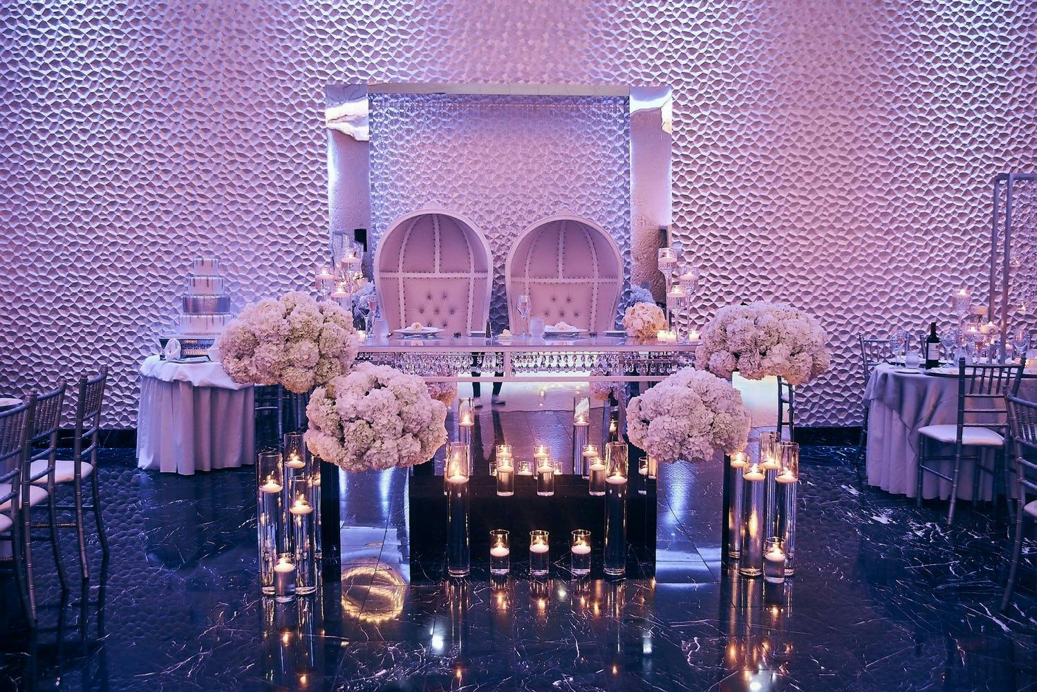 Purple Uplit Wedding With Modern Sweetheart Table Featuring Mirrored Elements, Candlelight, and Unique Seating | PartySlate