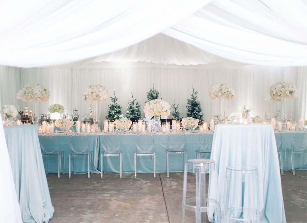 A wedding reception with a blue tablescape and white draping.
