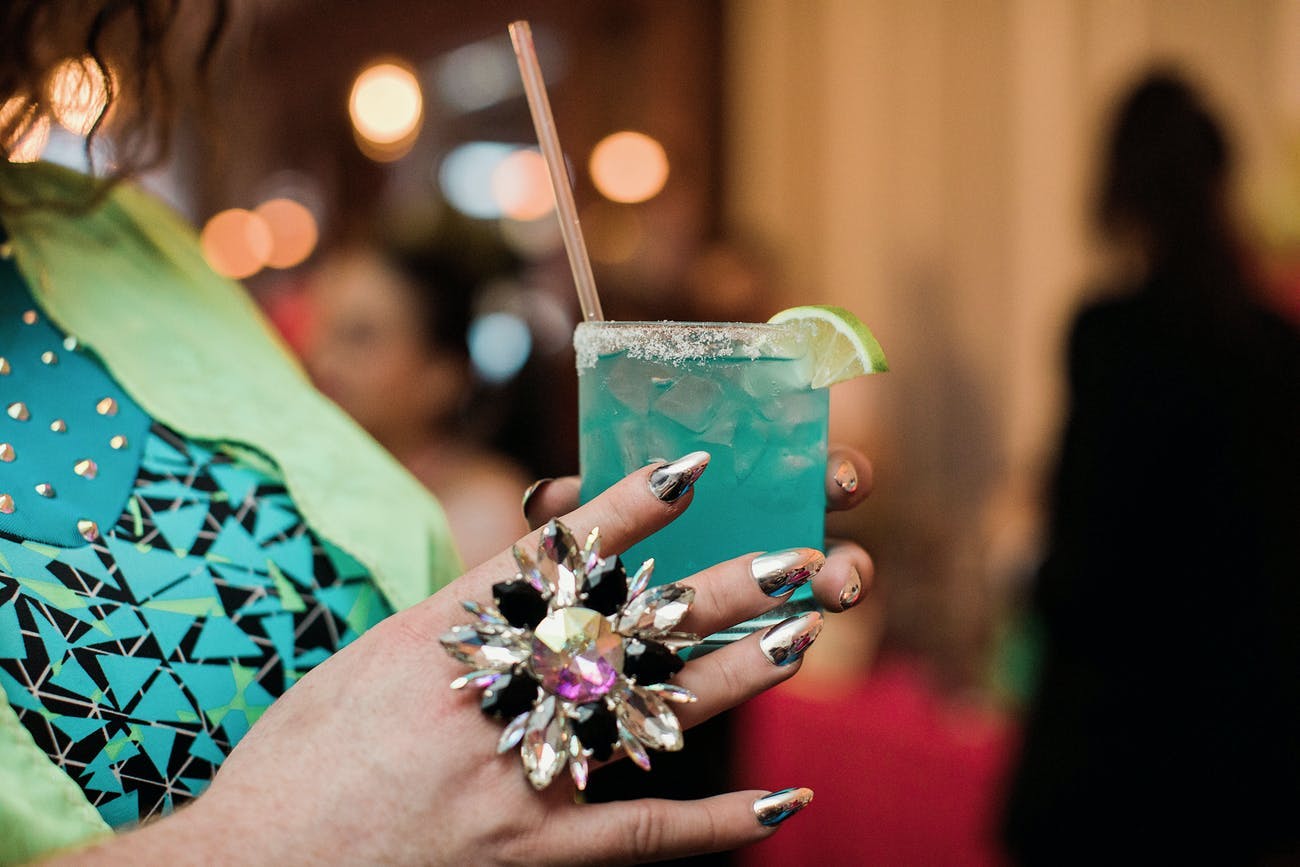 Hand Wearing Flashy Ring Holds a Neon Blue Cocktail | PartySlate