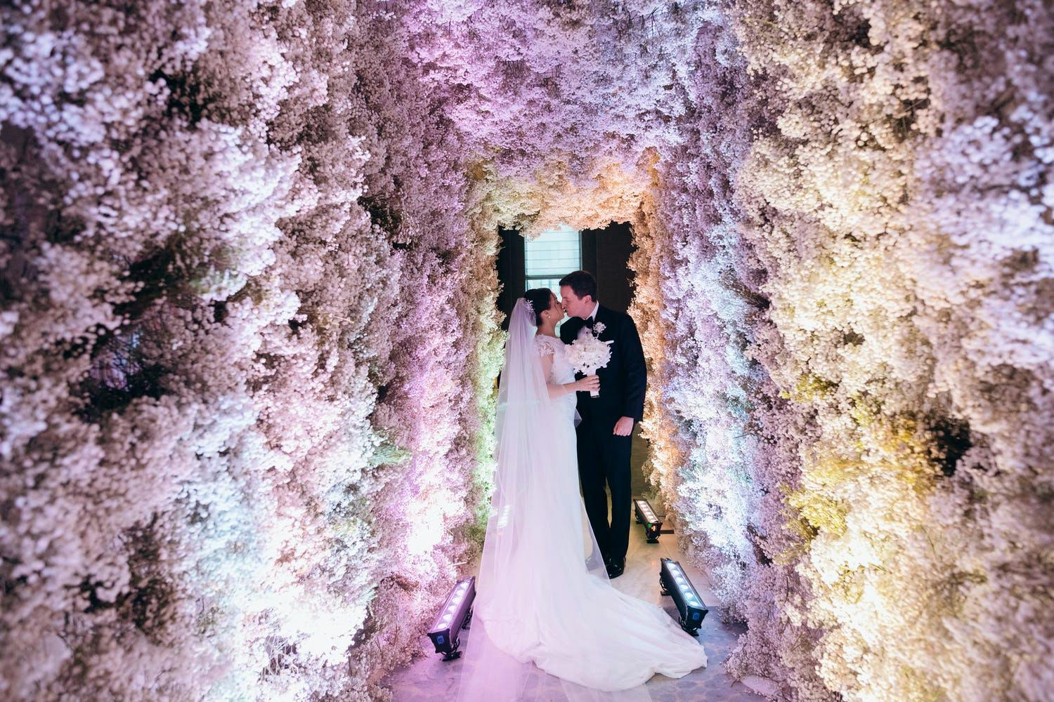 Bride and Groom Kiss in Wedding Entrance Made of Pure Baby's Breath | PartySlate