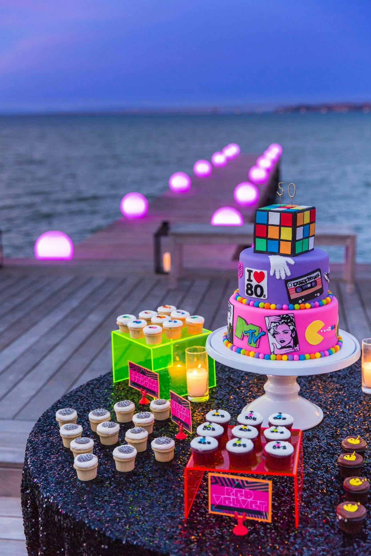 Beach Scene With Wooden Pier With Pink Neon Lights and 80s Party Dessert Station | PartySlate