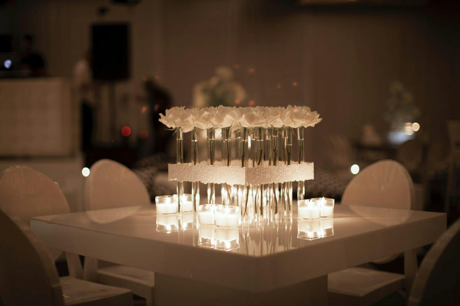 Modern Wedding All-White Wedding Tablescape With Square of Long-Stemmed White Flowers and Candlelight | PartySlate