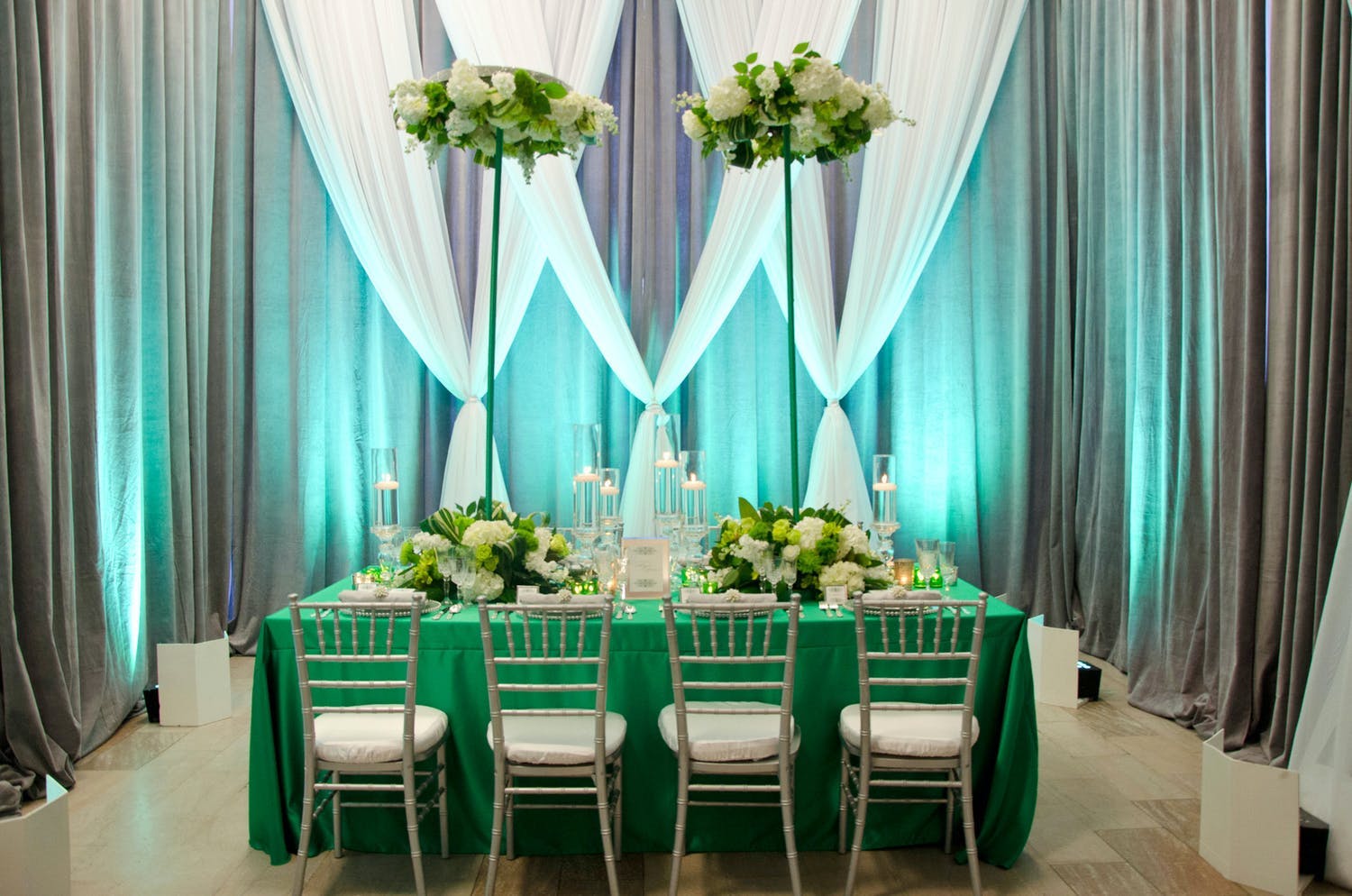 Modern Wedding Tablescape With Green Linen, Elevated Parasol-Like Greenery Centerpieces, and Sheer White, Green, and Gray Wall Draping | PartySlate