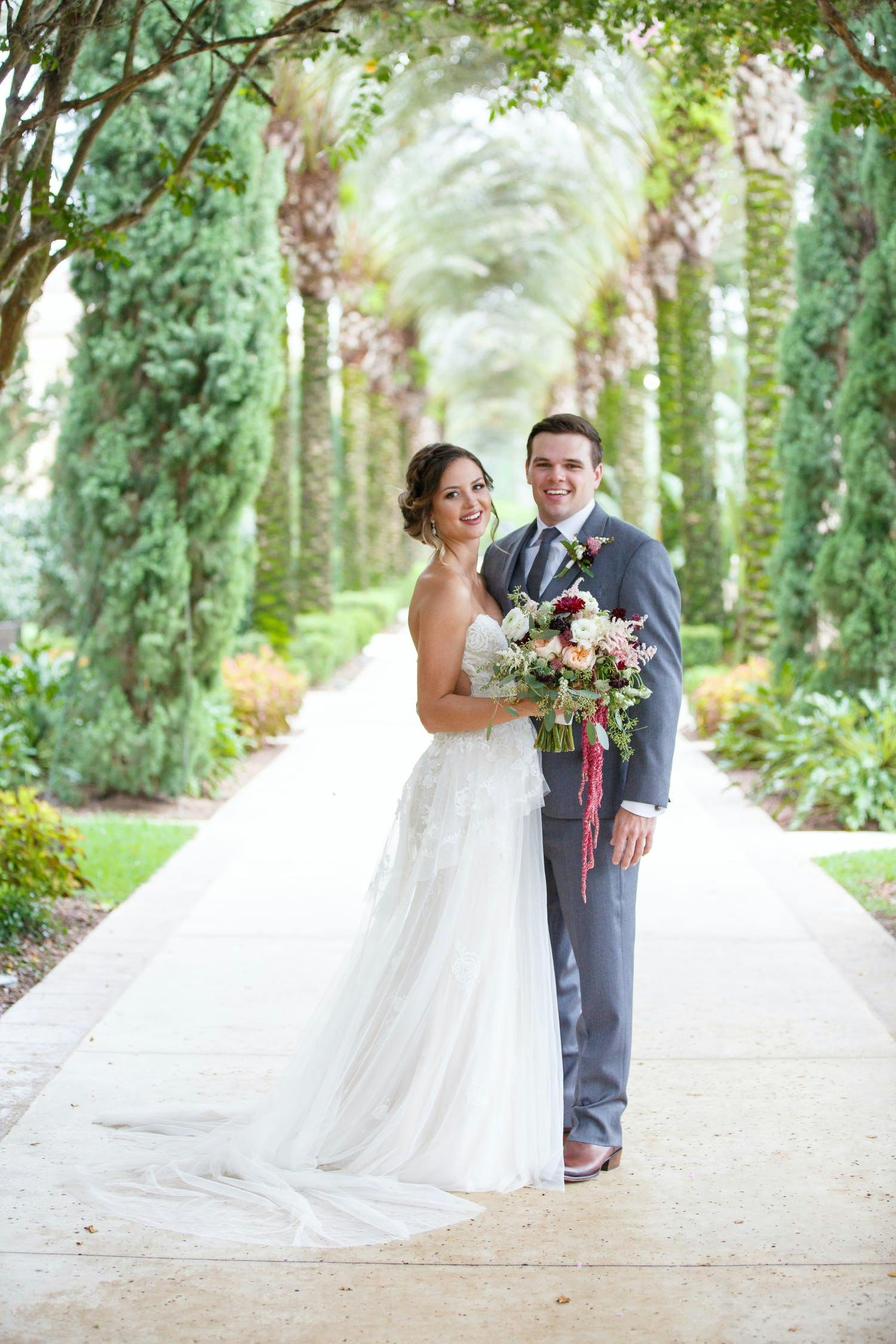 BRIDE AND GROOM OUTSIDE AT FOUR SEASONS ORLANDO AT WALT DISNEY WORLD® RESORT WITH LUSH BACKGROUND | PARTYSLATE