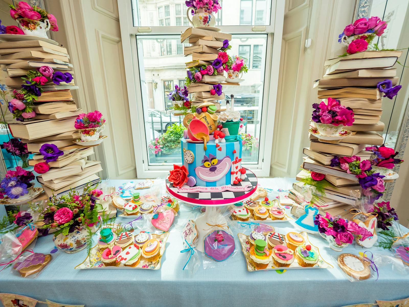 Kids 4th Birthday Alice in Wonderland Themed Tea Party Celebration with Mad Hatter and Chesire Cat Tiered Cake with Books On Top | PartySlate
