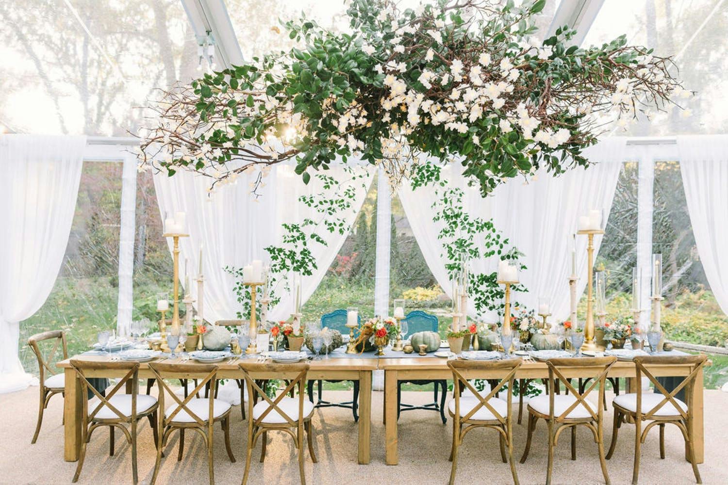 Rustic Wedding Tablescape With White Drapery and Overhanging Greenery | PartySlate
