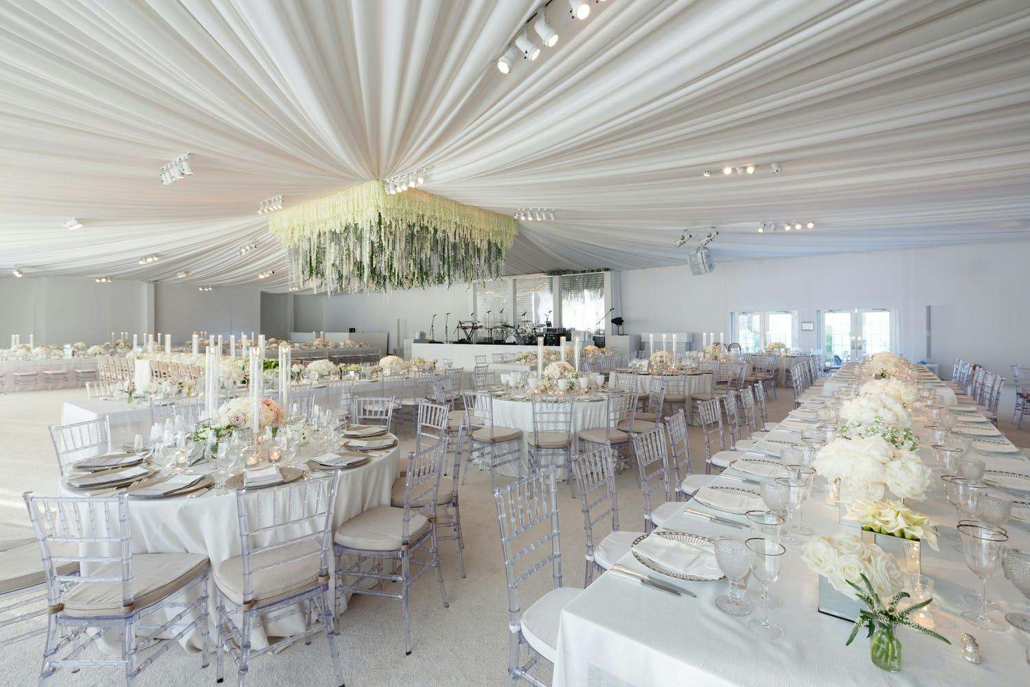 All-White Wedding Tent With Sheer Ceiling Drapery and Suspended Square Floral Focal Point | PartySlate