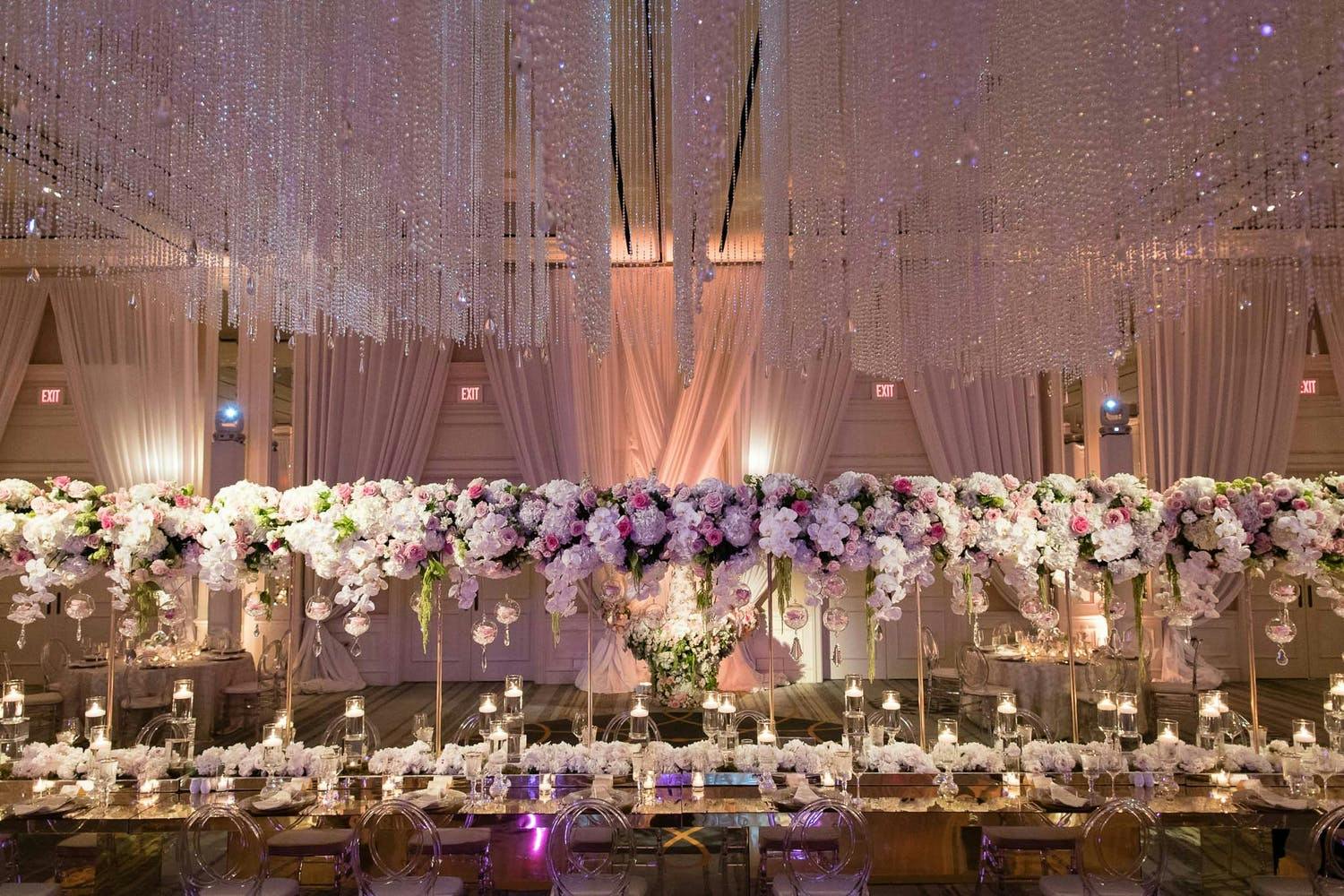 Ballroom Wedding Reception With Elevated White and Purple Floral Centerpieces and Suspended Crystal Wedding Ceiling Decorations | PartySlate