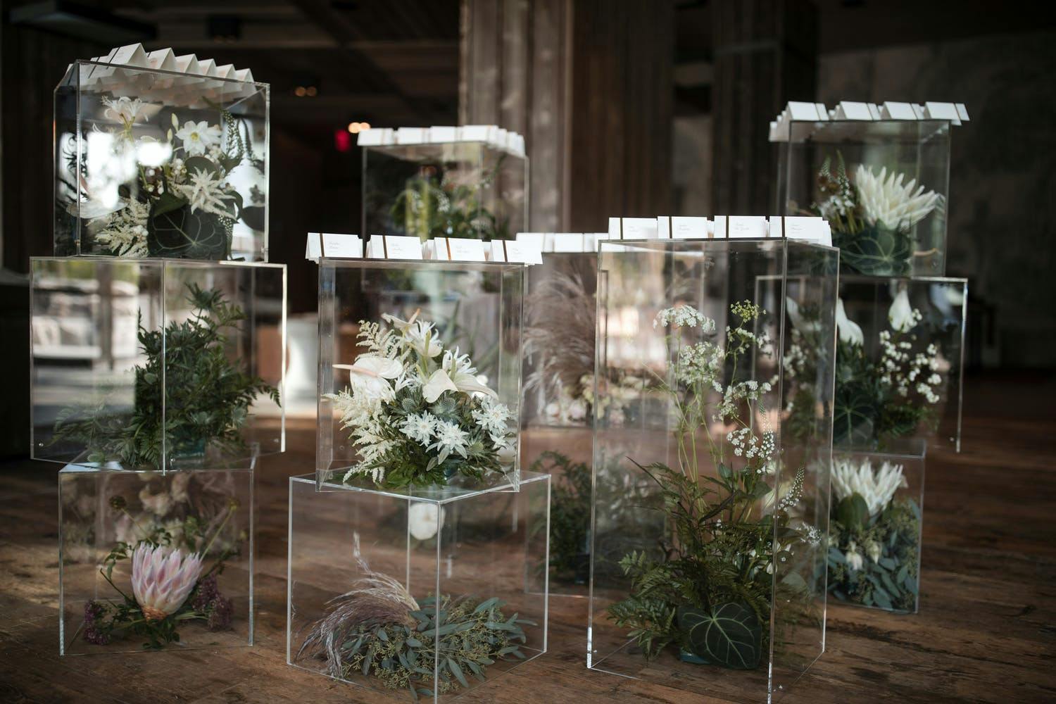Lucite Boxes Filled With Tropical Flowers and Topped with White Wedding Escort Cards | PartySlate