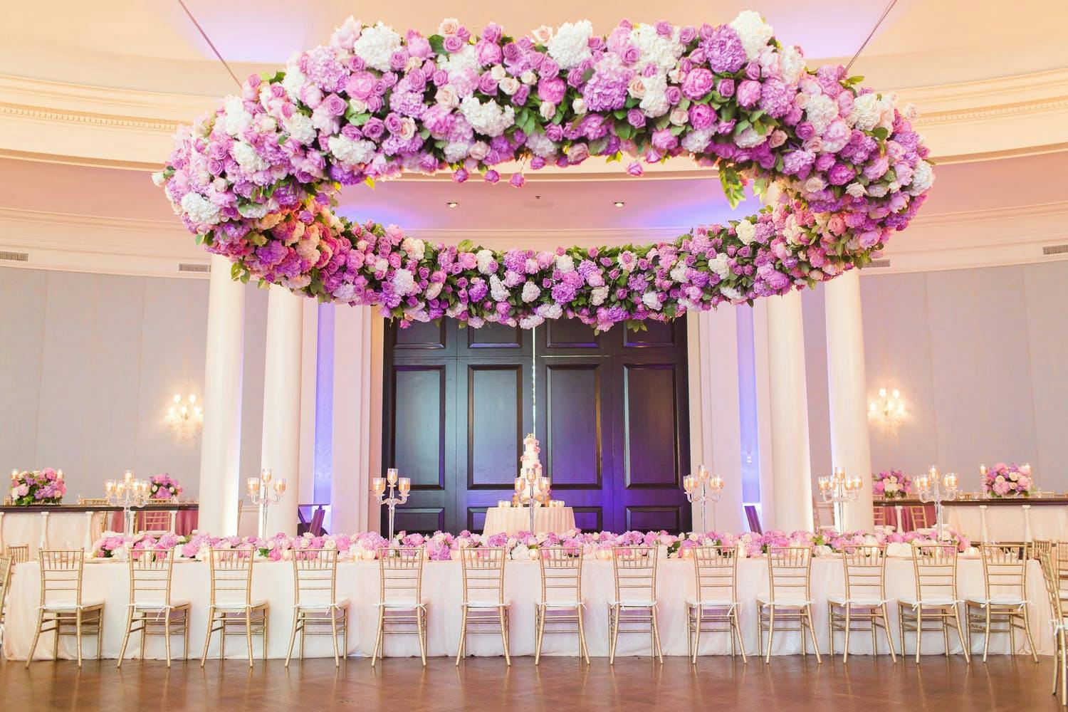 Wedding Ballroom in Peach and Neutral Tones With Suspended Giant Circular Wreathe of Pink and Purple Flowers | PartySlate
