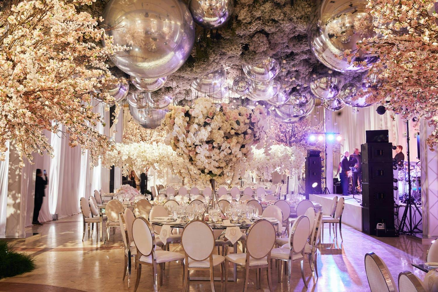 Роскошная свадьба с пышными потолочными украшениями из серебристых воздушных шаров и белых цветов | PartySlate