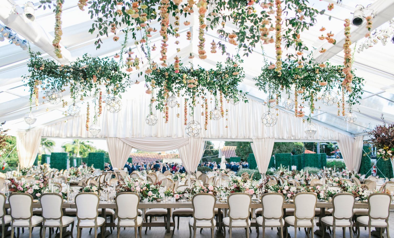 White Wedding Tent With Suspended Floral Fringe and Greenery Wreathes | PartySlate