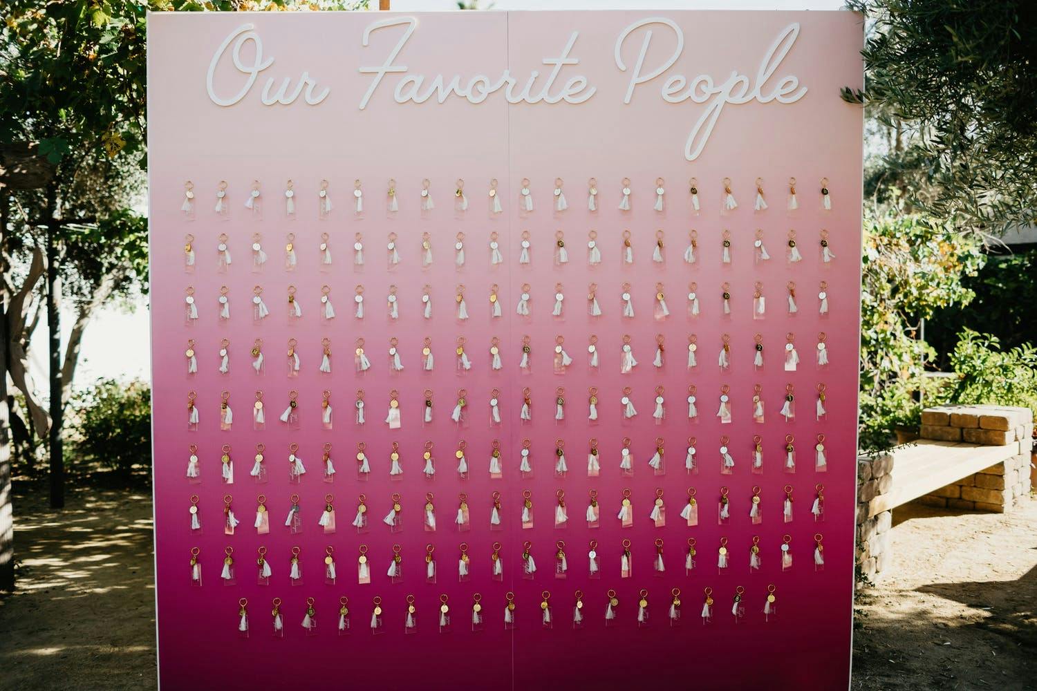 Wedding Seating Chart in Ombré Pink With Party Favor KeyChains Attached to Name Tags | PartySlate