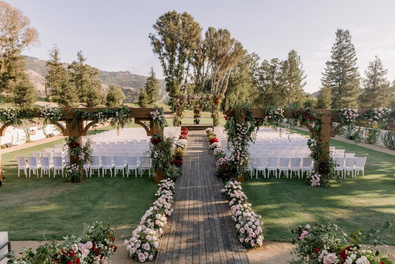 Rustic Outdoor Wedding Aisle With Beautiful Florals and a Wooden Walkway | PartySlate
