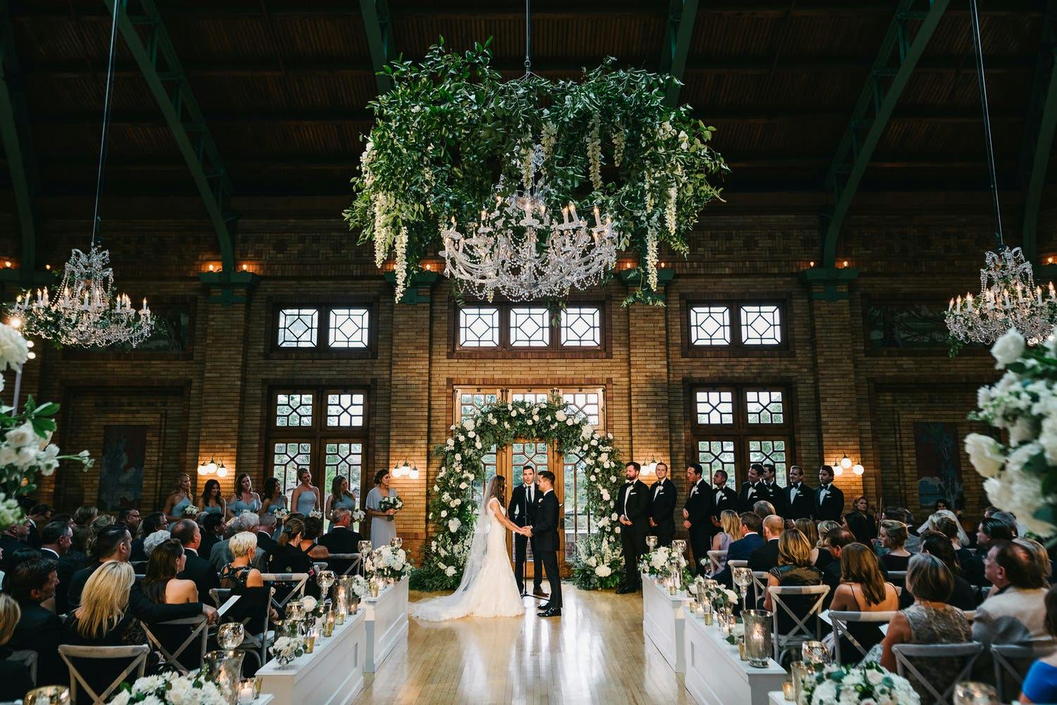Wedding Ceremony at Cafe Brauer at Lincoln Park Zoo With Glittering Chandelier With Cascading Tendrils of Greenery | PartySlate