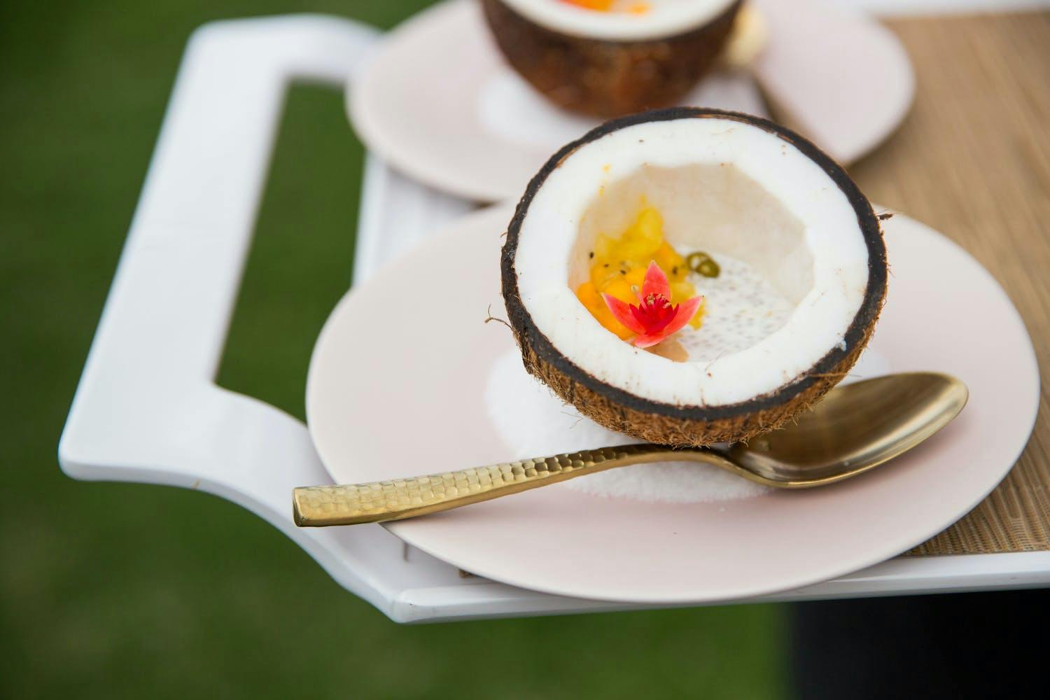 Half of Coconut With Bright Orange Flower and Spoon on White Plate | PartySlate