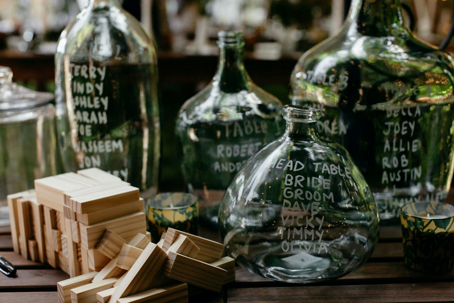 Table With Vintage Glass Jars Inscribed With Wedding Table Numbers and Guests' Names | PartySlate