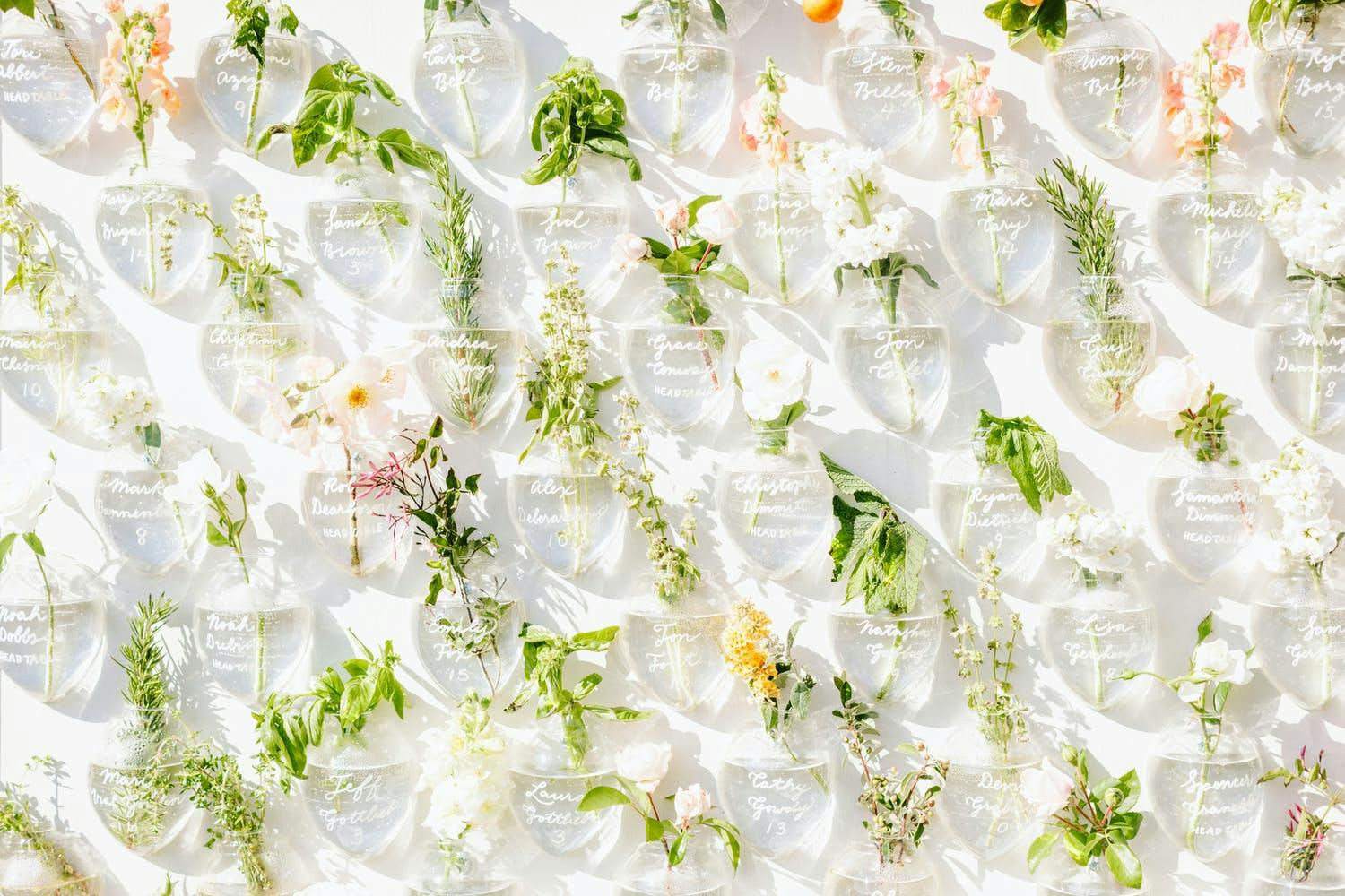 Wedding Seating Backdrop With Inscribed Vases and Bright Flowers | PartySlate
