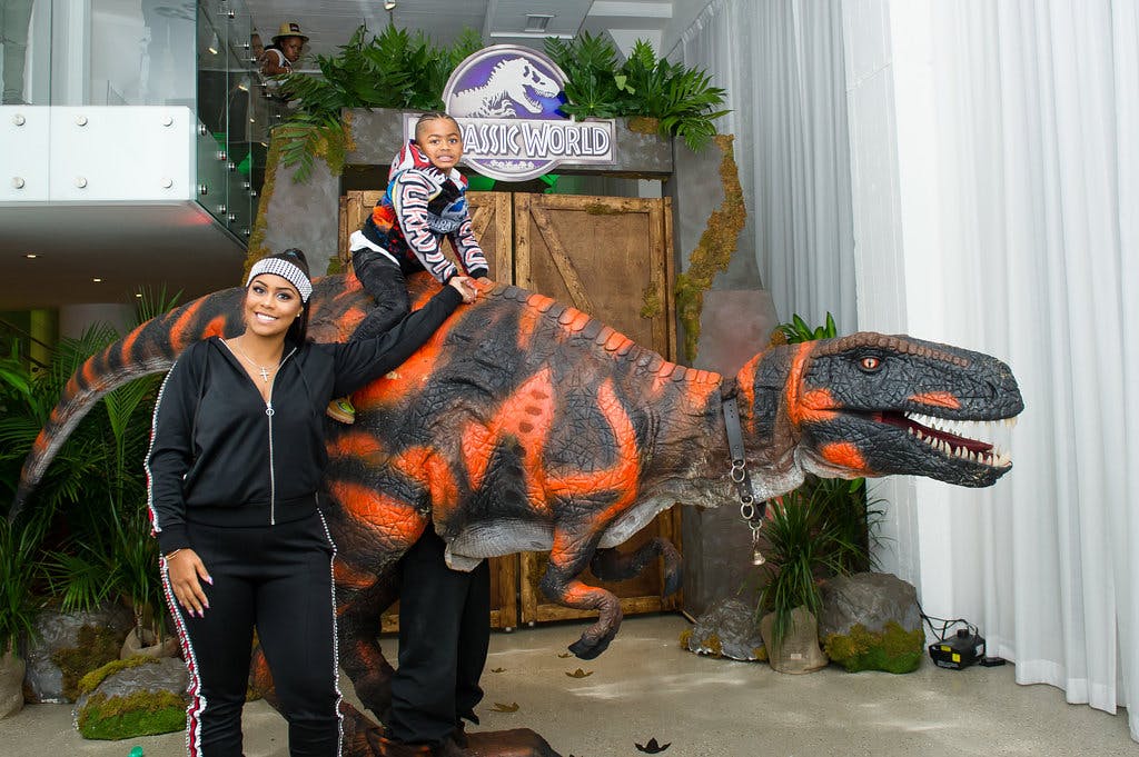 Little Boy Sitting On Top a Life-Like Dinosaur at 5th Jurassic Dinosaur Themed Birthday Party | PartySlate