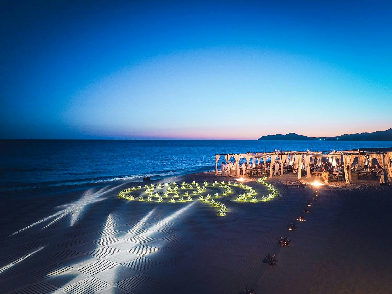 Beach Wedding With Star-Shaped Light Projections and Spiral Maze of Gold Star-Shaped Lanterns | PartySlate