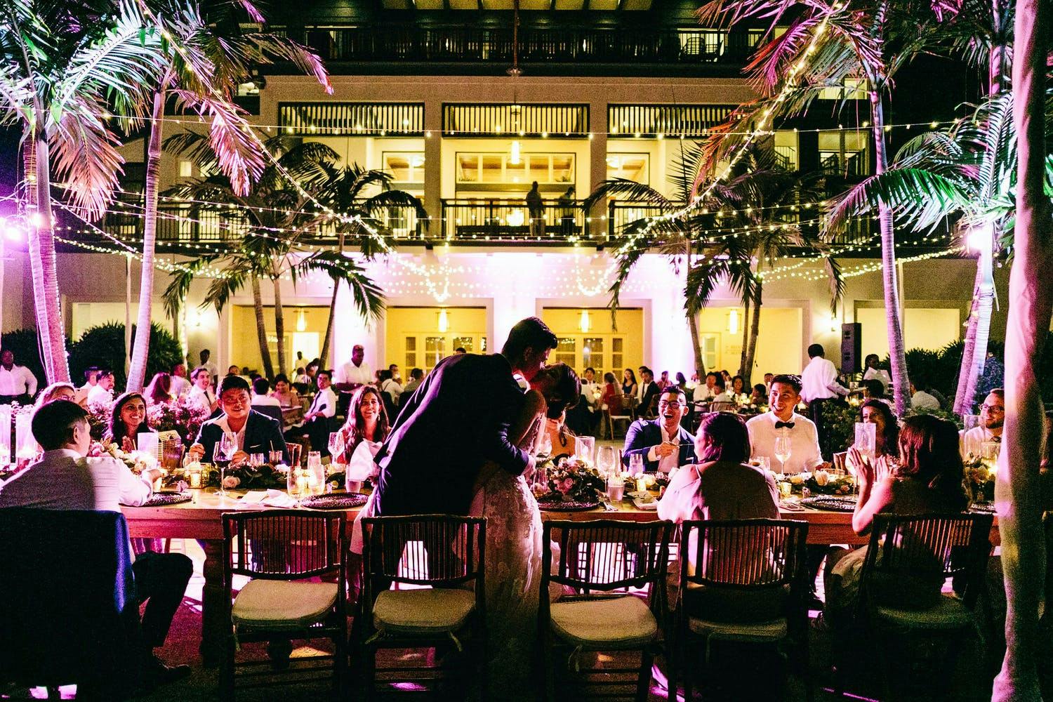 Tropical Courtyard Wedding With Pink Uplit Palm Trees and Overhead Fairy Lights | PartySlate