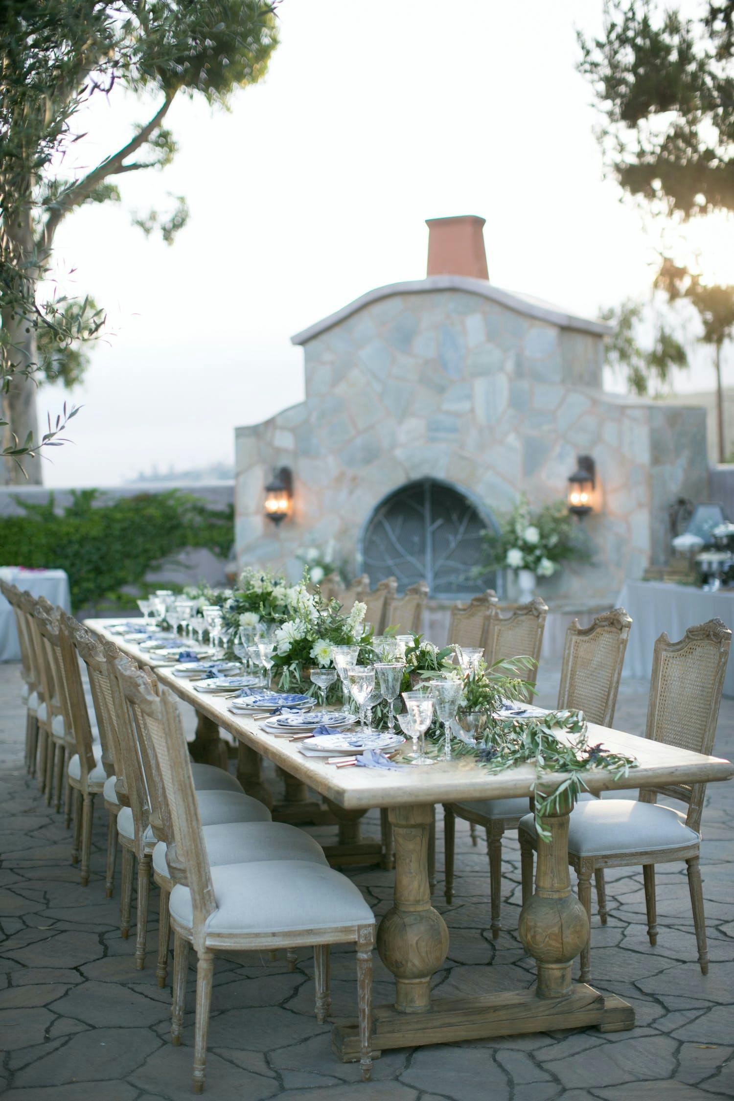Outdoor dinner party with wicker chairs and garland draped table