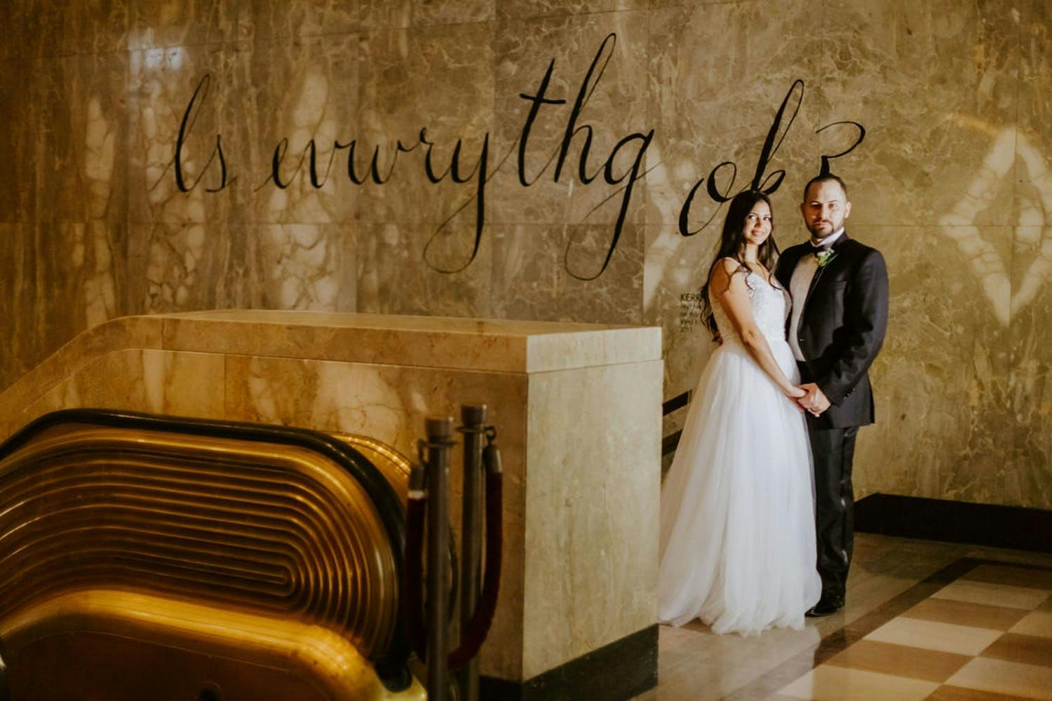 Bride and Groom Pose in Lobby of The Historic Alfred I. Dupont Building | PartySlate