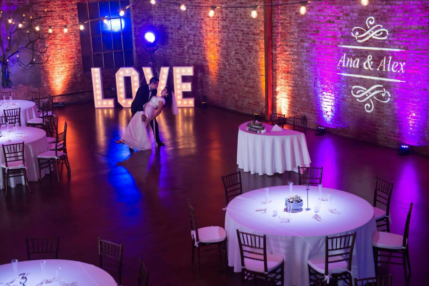 Industrial Wedding Venue With Monogram Lighting on Exposed Brick | PartySlate
