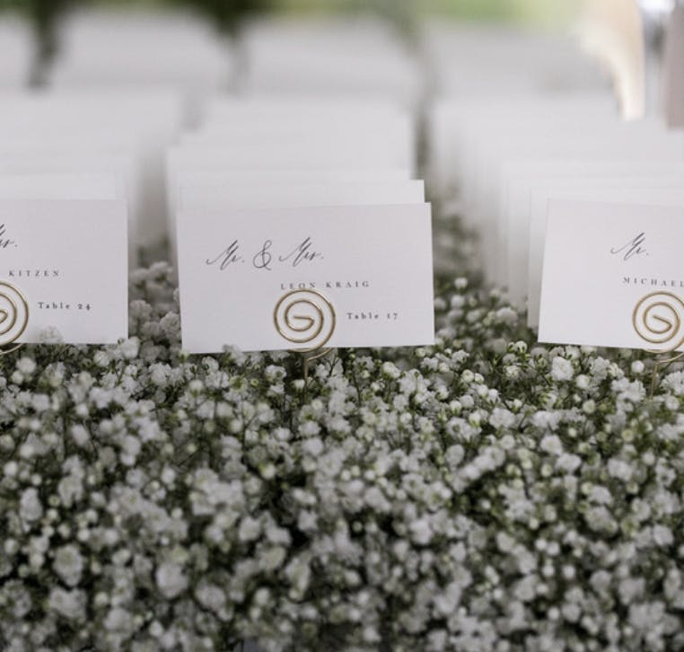 White Wedding Seating Cards on a Bed of Baby’s Breath