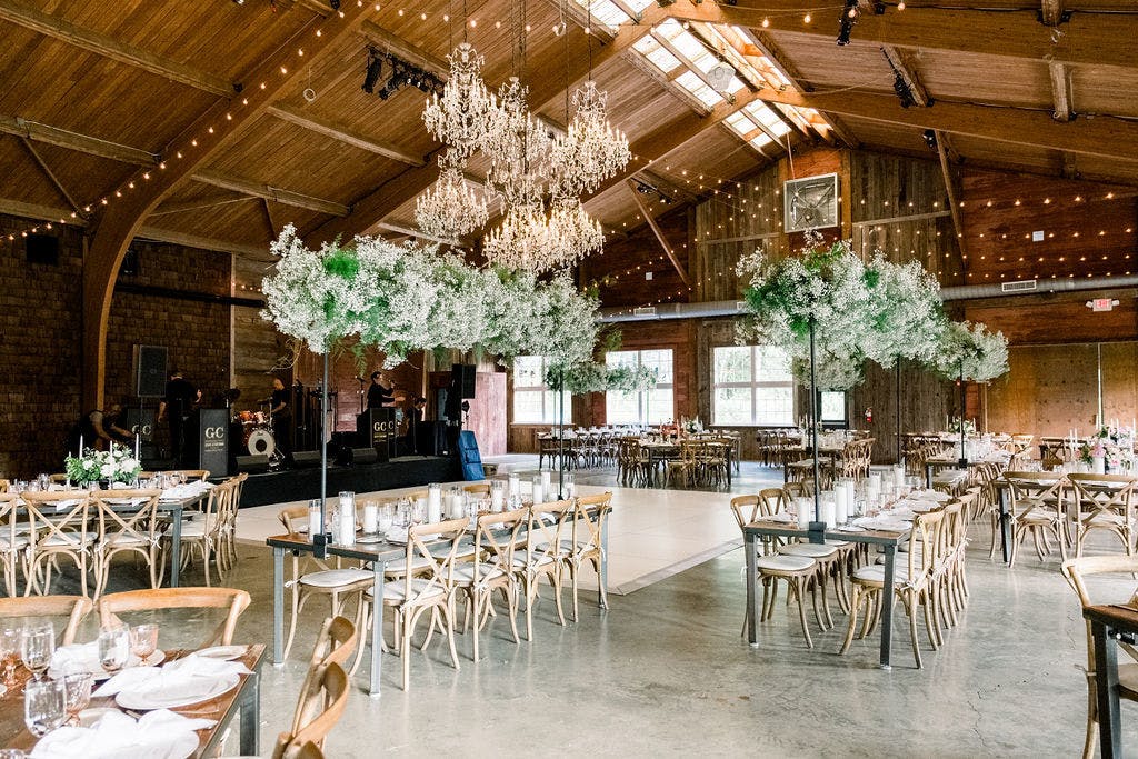 Rustic Barn Wedding Reception With Elevated Baby’s Breath and Greenery Wedding Centerpieces | PartySlate