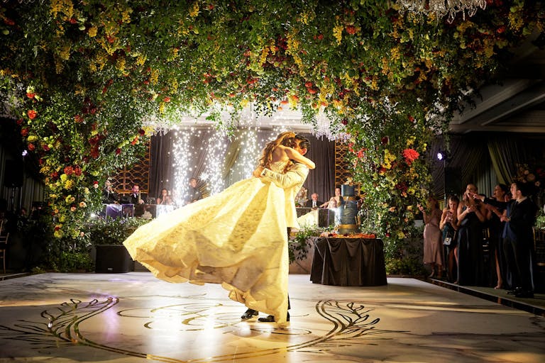 Groom Picks Up Bride on Dance Floor Under Arched Greenery at Four Seasons Hotel Chicago | PartySlate
