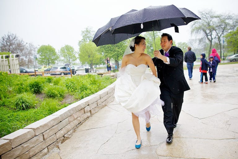 Bride and Groom Walk Through Peggy Notebaert Nature Museum Under a Black Umbrella | PartySlate