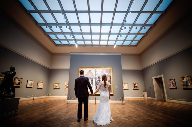 Bride and Groom Hold Hands While Viewing Paris Street; Rainy Day at The Art Institute of Chicago | PartySlate