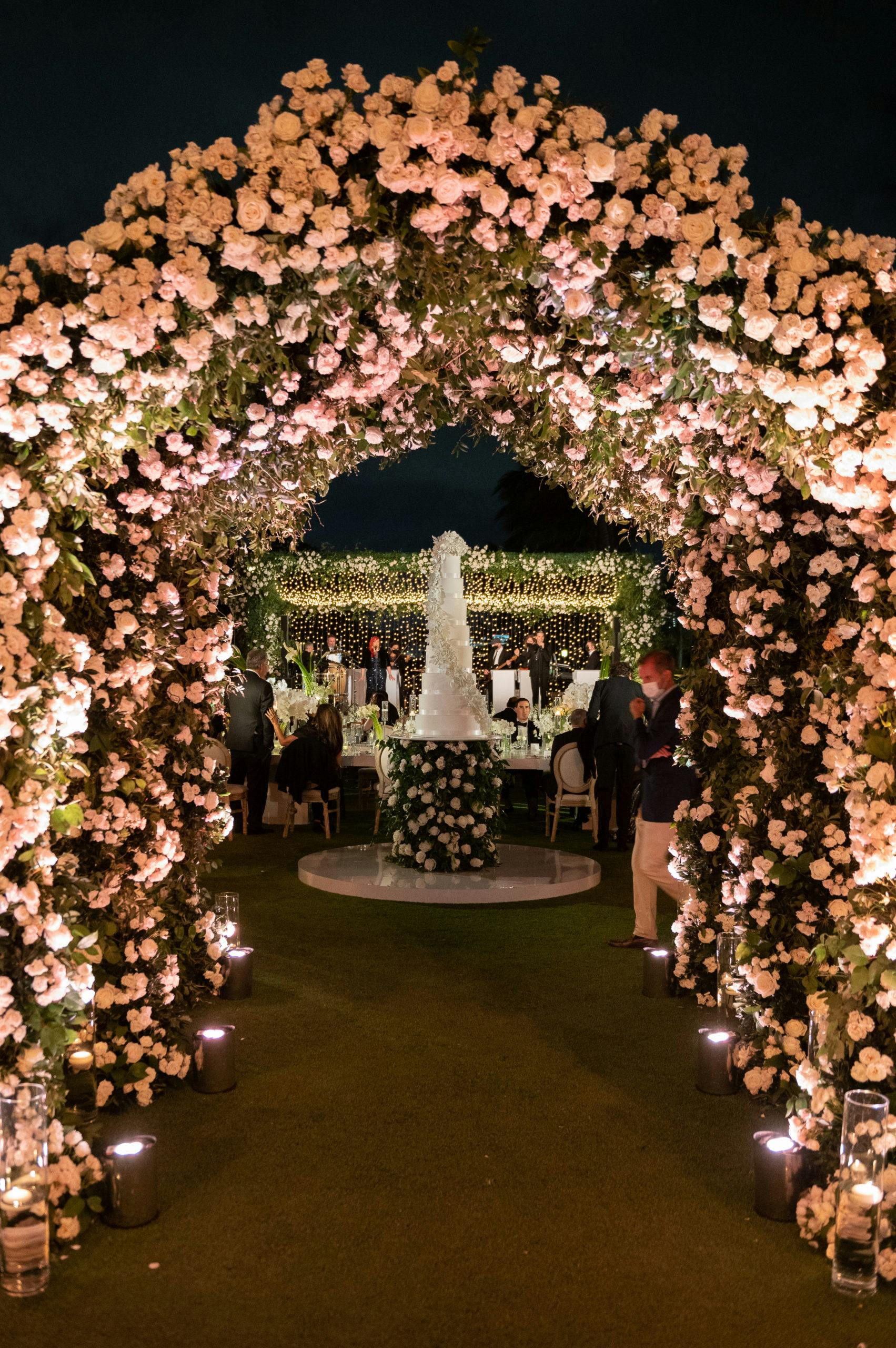 Pink Floral Wedding Arch Leading to Wedding Cake at Wedding Planned by YSD Events | PartySlate