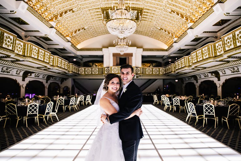 Bride and Groom Embrace on White LED Dance Floor in Opulent Ballroom at Millennium Knickerbocker Hotel
