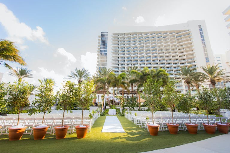 Outdoor Lawn Wedding Ceremony with Eden Roc Miami Beach in Background | PartySlate