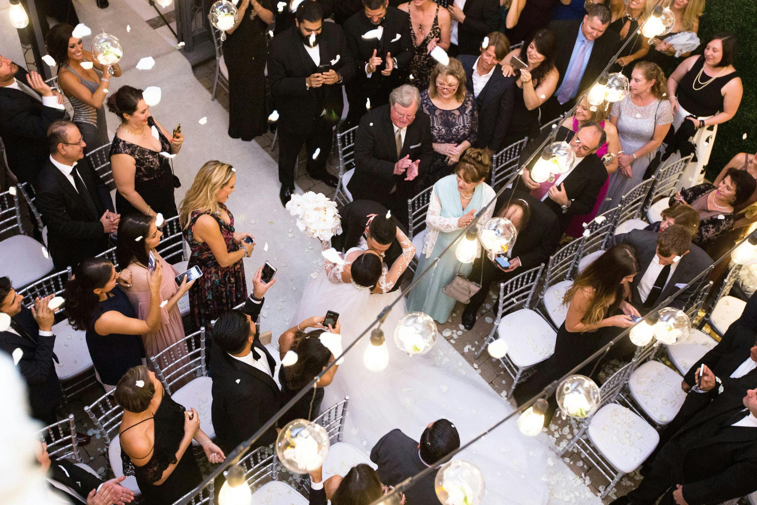 Aerial view of a wedding reception and bride and groom kissing in middle of aisle | PartySlate