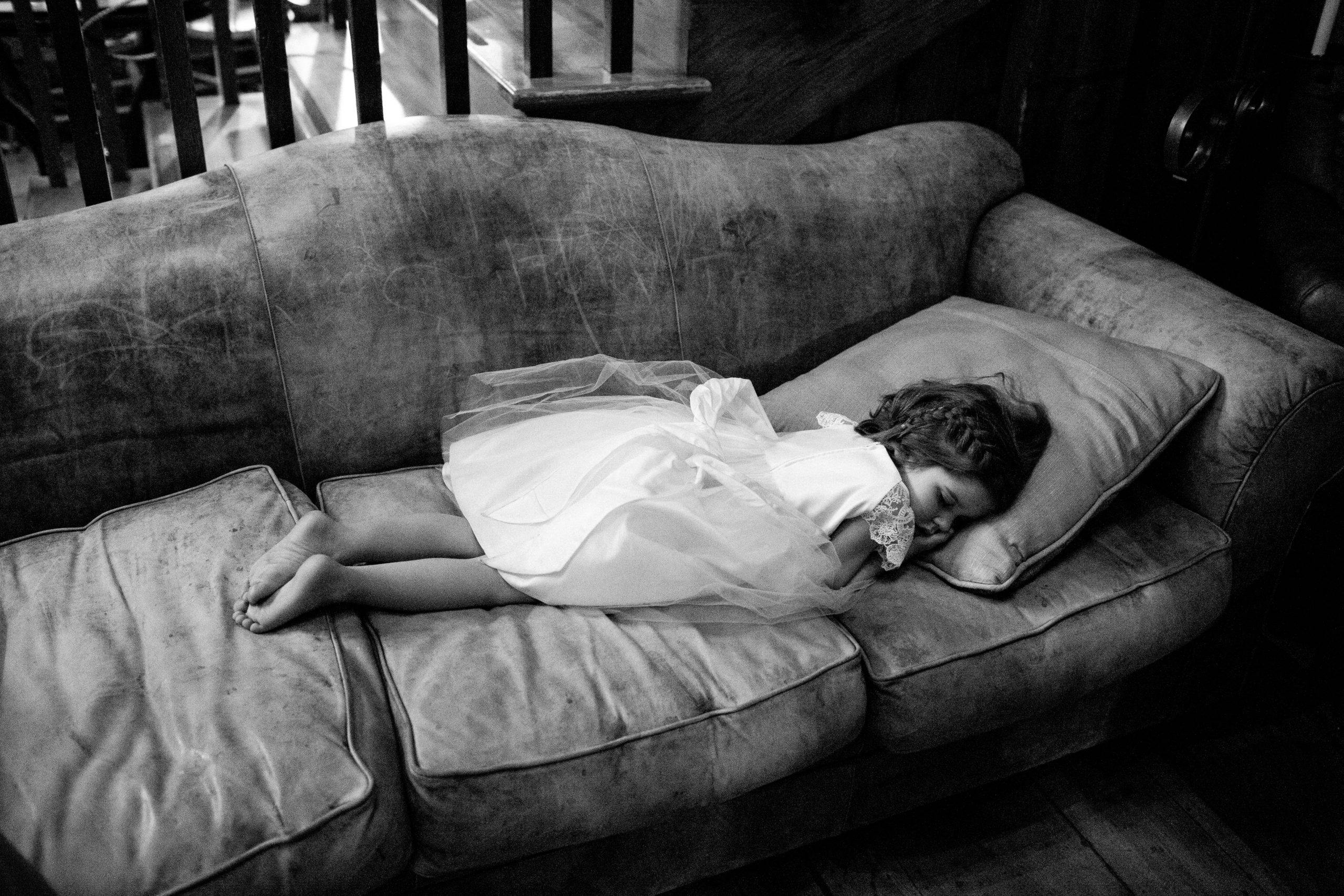 Flower girl peacefully sleeping on couch | PartySlate