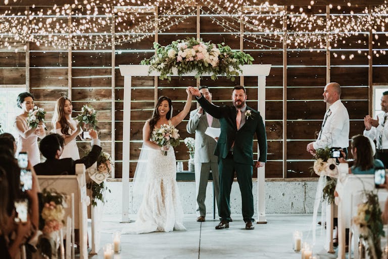 Newlywed couple at floral alter under twinkling lights at Heritage Prairie Farm in Elburn, IL | PartySlate