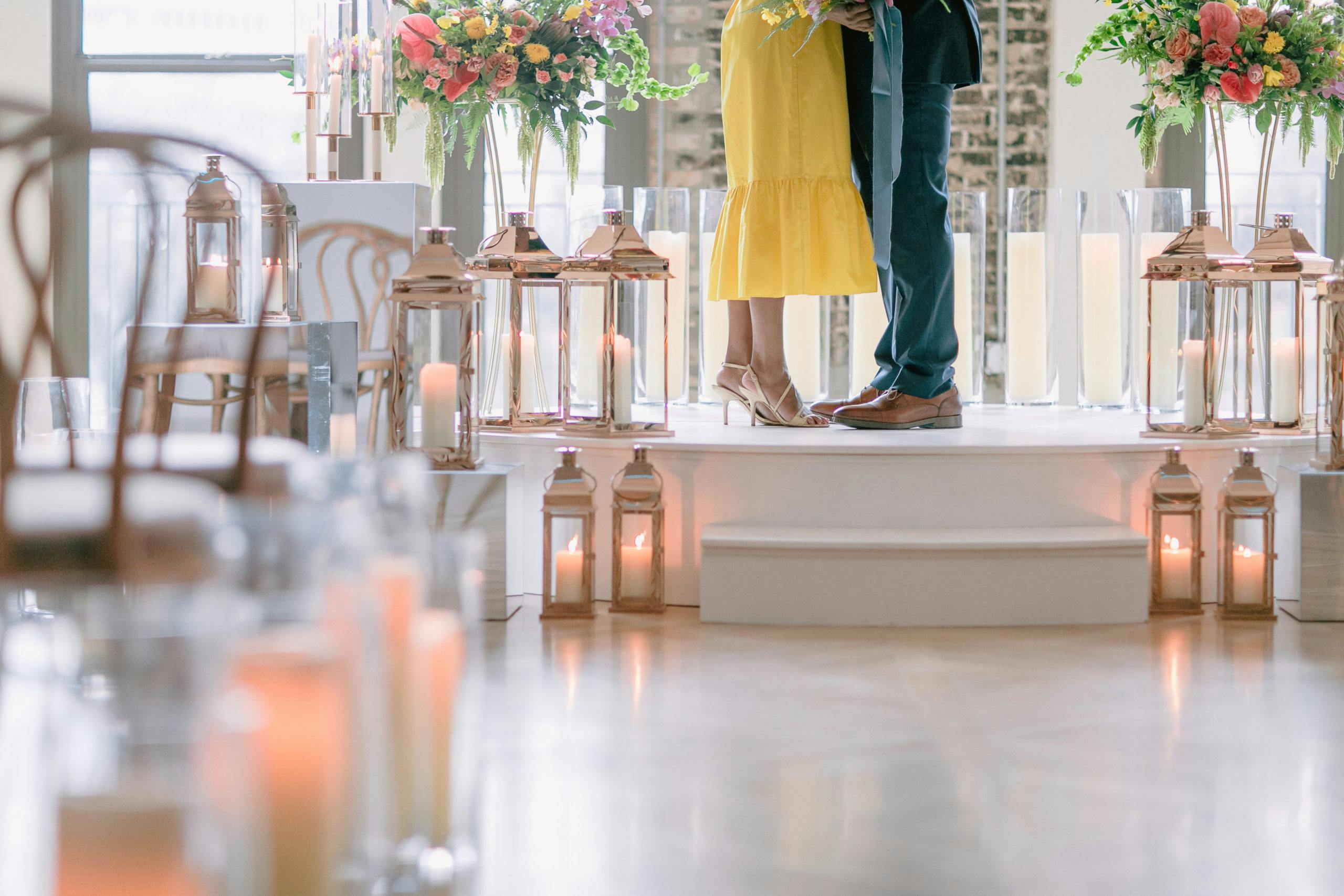 feet shot of aisle lit with lanterns and bride in yellow dress l PartySlate