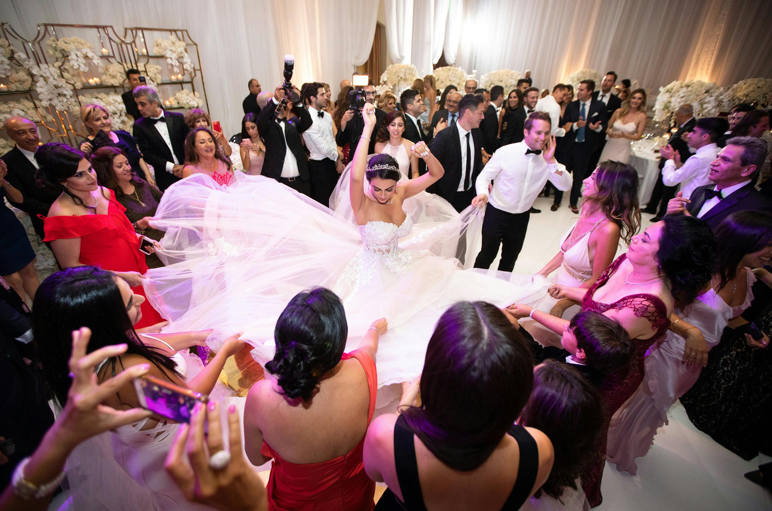 Bride twirling to showcase her dress on dance floor surrounded by wedding guests | PartySlate