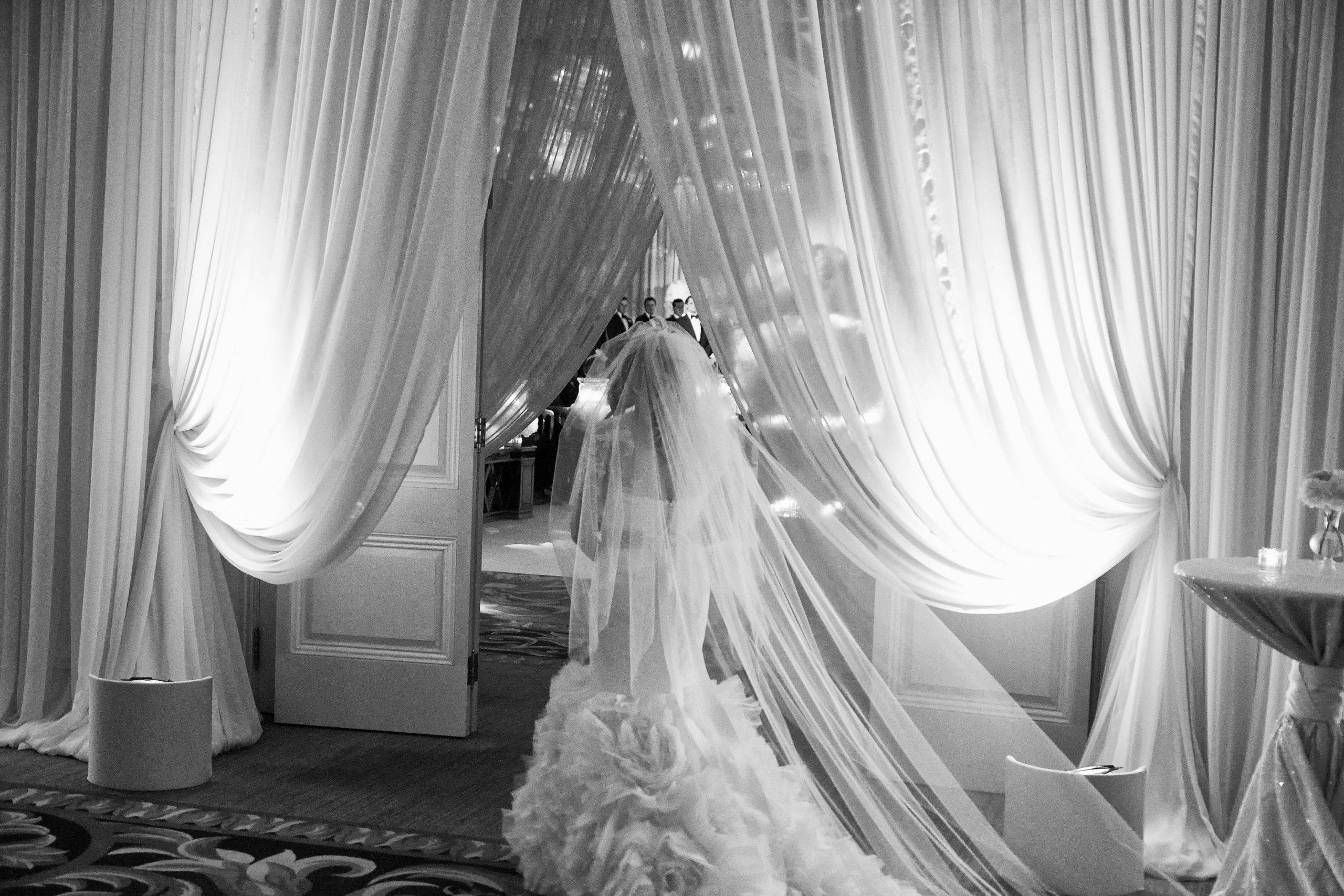 Black and white photo of bride looking into ballroom | PartySlate