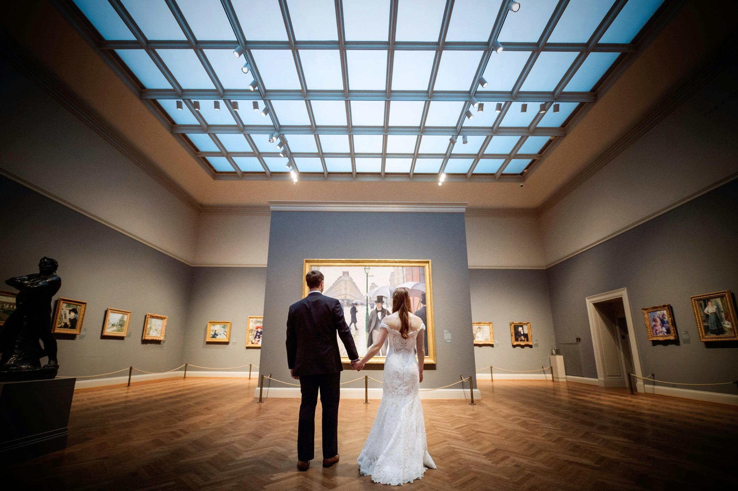 Shot of bride and groom from behind looking at art in museum | PartySlate