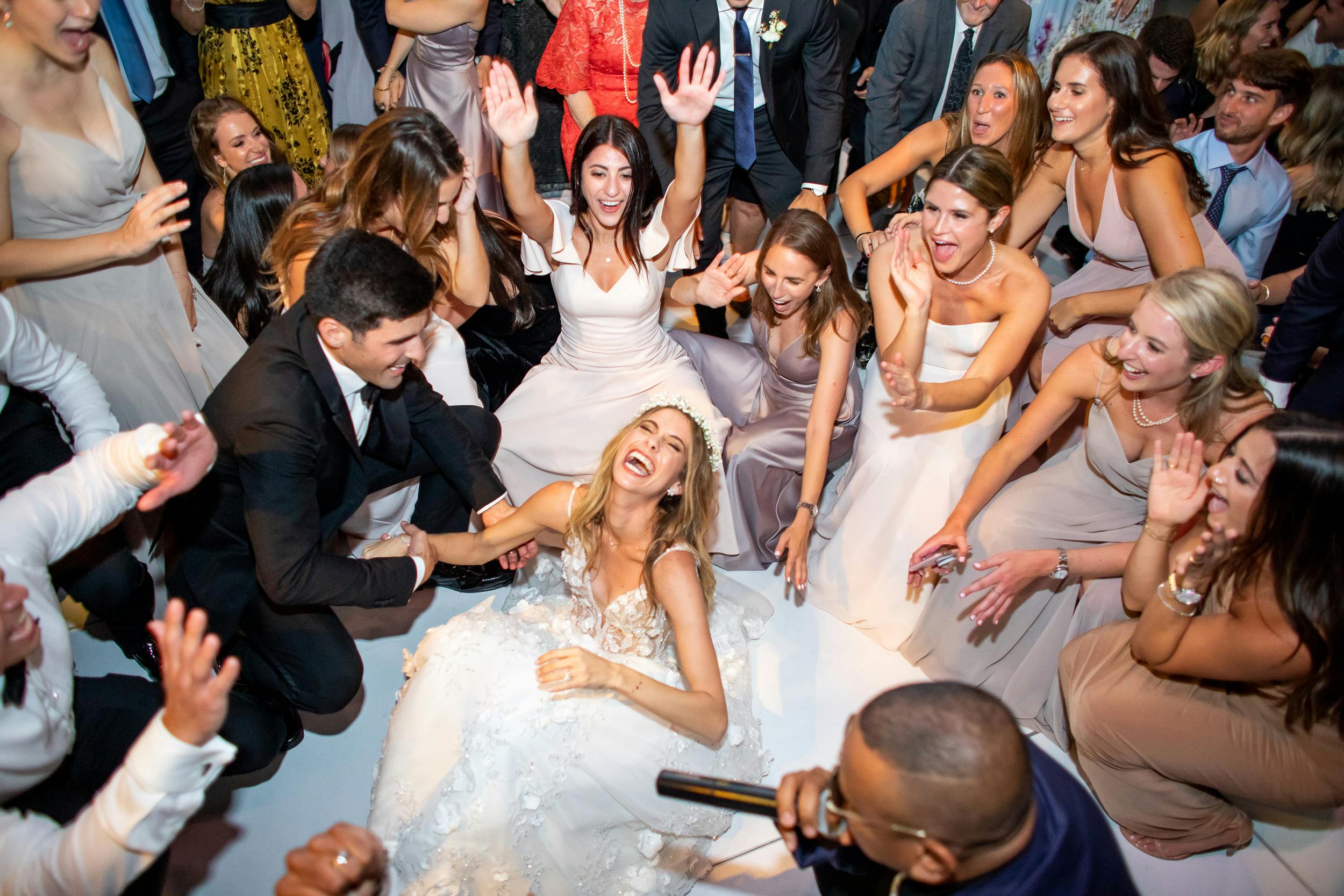 Bride, groom and friends dancing and laughing on dance floor during wedding reception | PartySlate